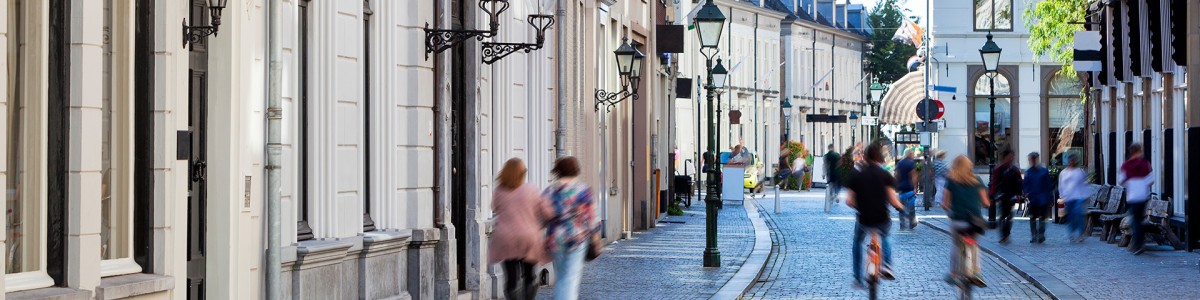 Een straat in Amsterdam waar mensen doorheen lopen. Er is een bewegingswaas bij de mensen.