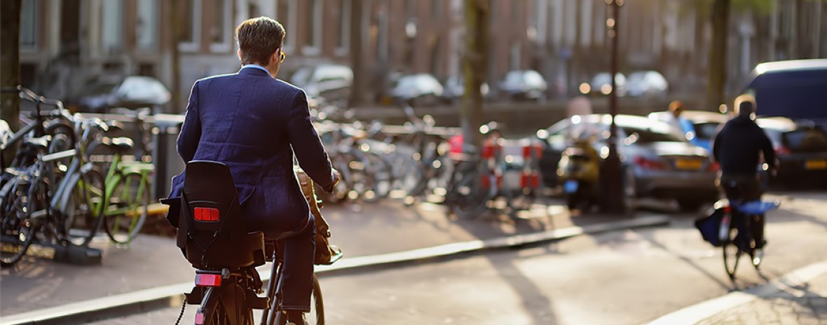 Een man fietst door een vrijwel lege straat in de stad. Hij heeft een kinderzitje achterop.